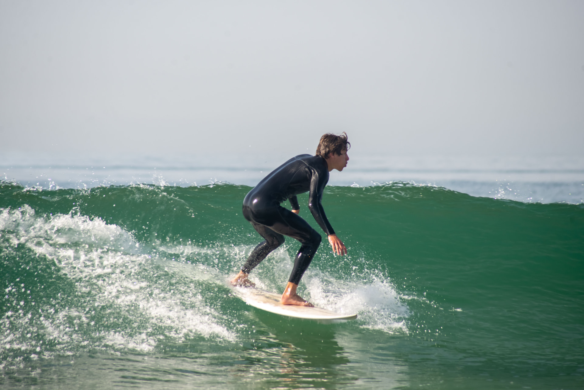 A surfer riding a clean green wave in Southwest Portugal